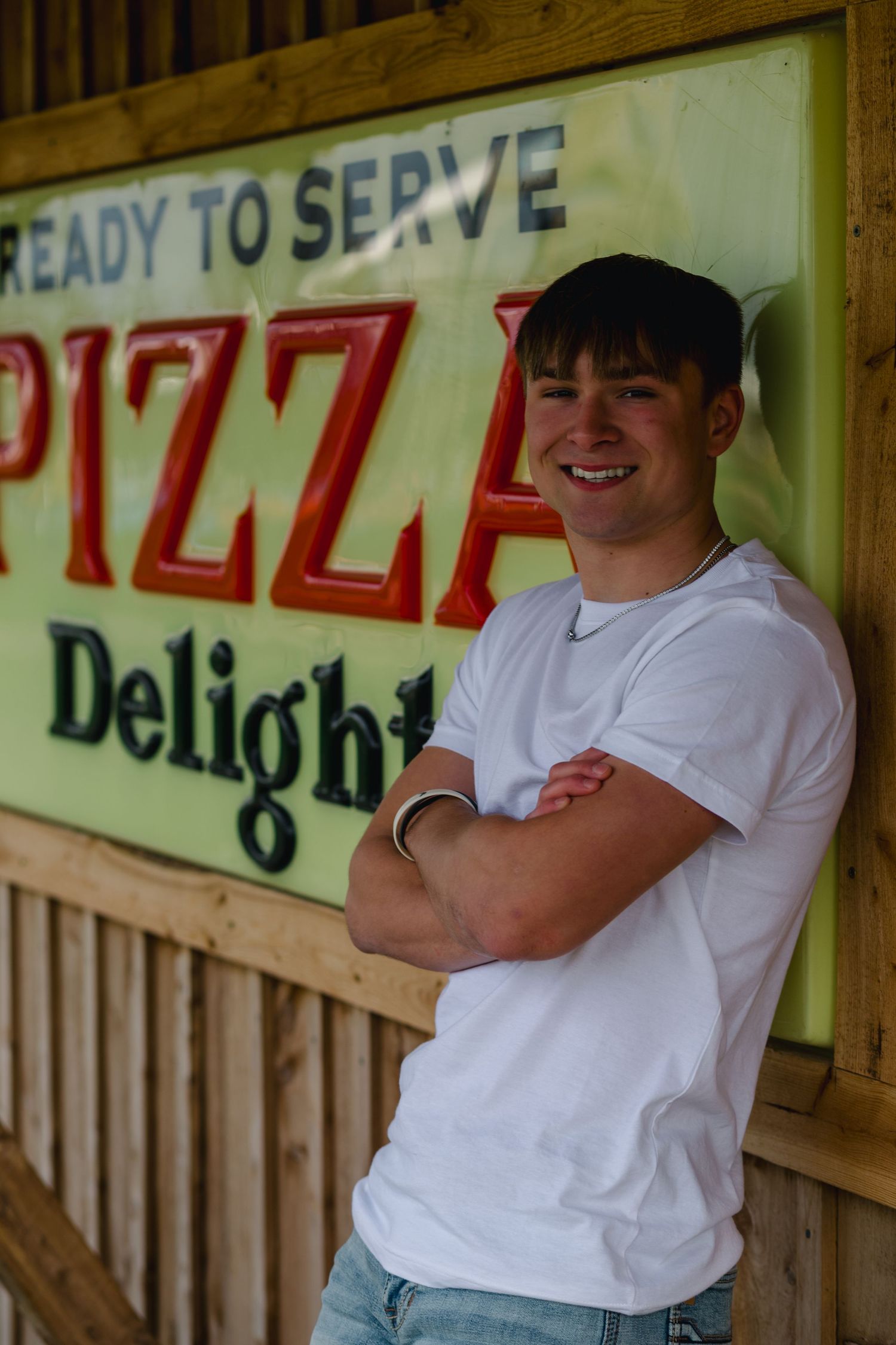 Staff in white uniforms stand against rustic wooden pizza parlor walls displaying vintage-style menu signage.