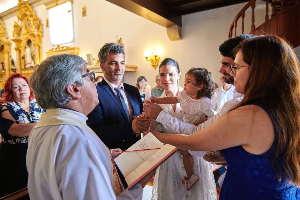 Family gathered around a priest during a baptism ceremony inside a decorated church.