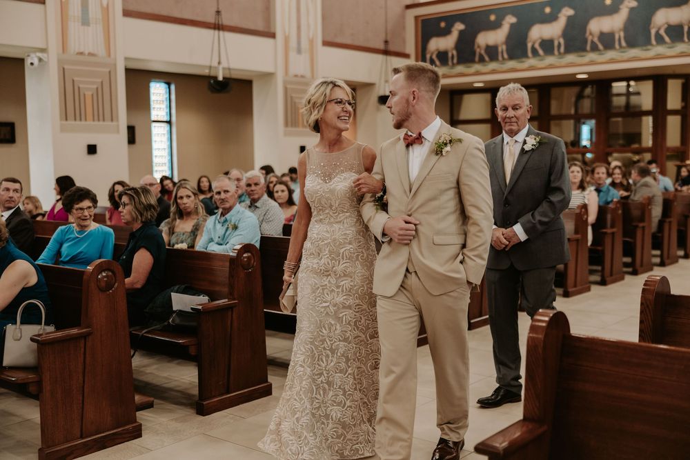 A romantic church wedding ceremony with guests seated in wooden pews.
