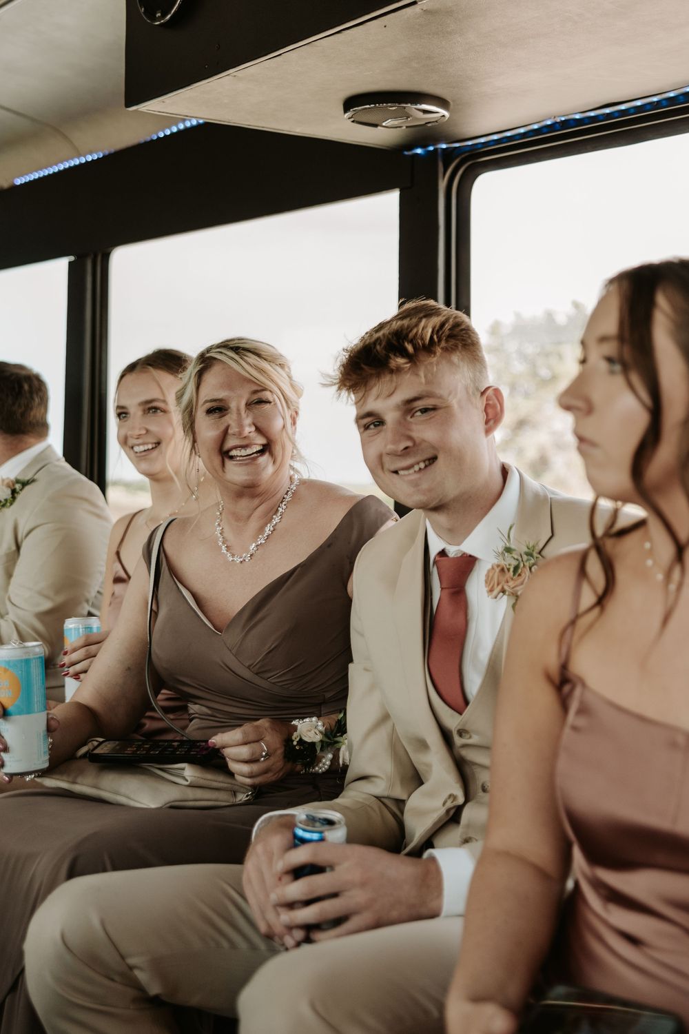 Wedding party members sharing laughs while riding together in a vehicle.