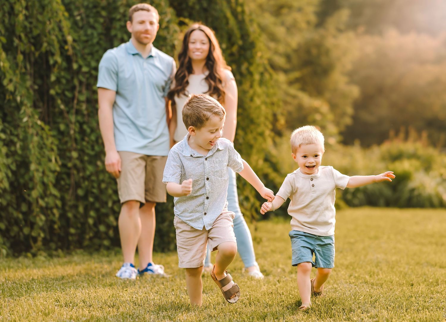 A group of people running and playing together in a sunlit grassy field during golden hour.