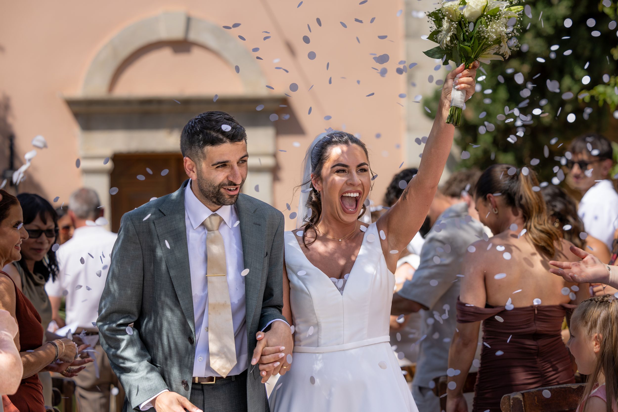 Wedding guests celebrating with confetti toss in outdoor setting.