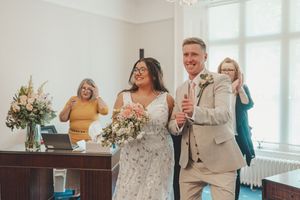 Wedding celebration in a bright indoor venue with guests dancing and laughing.
