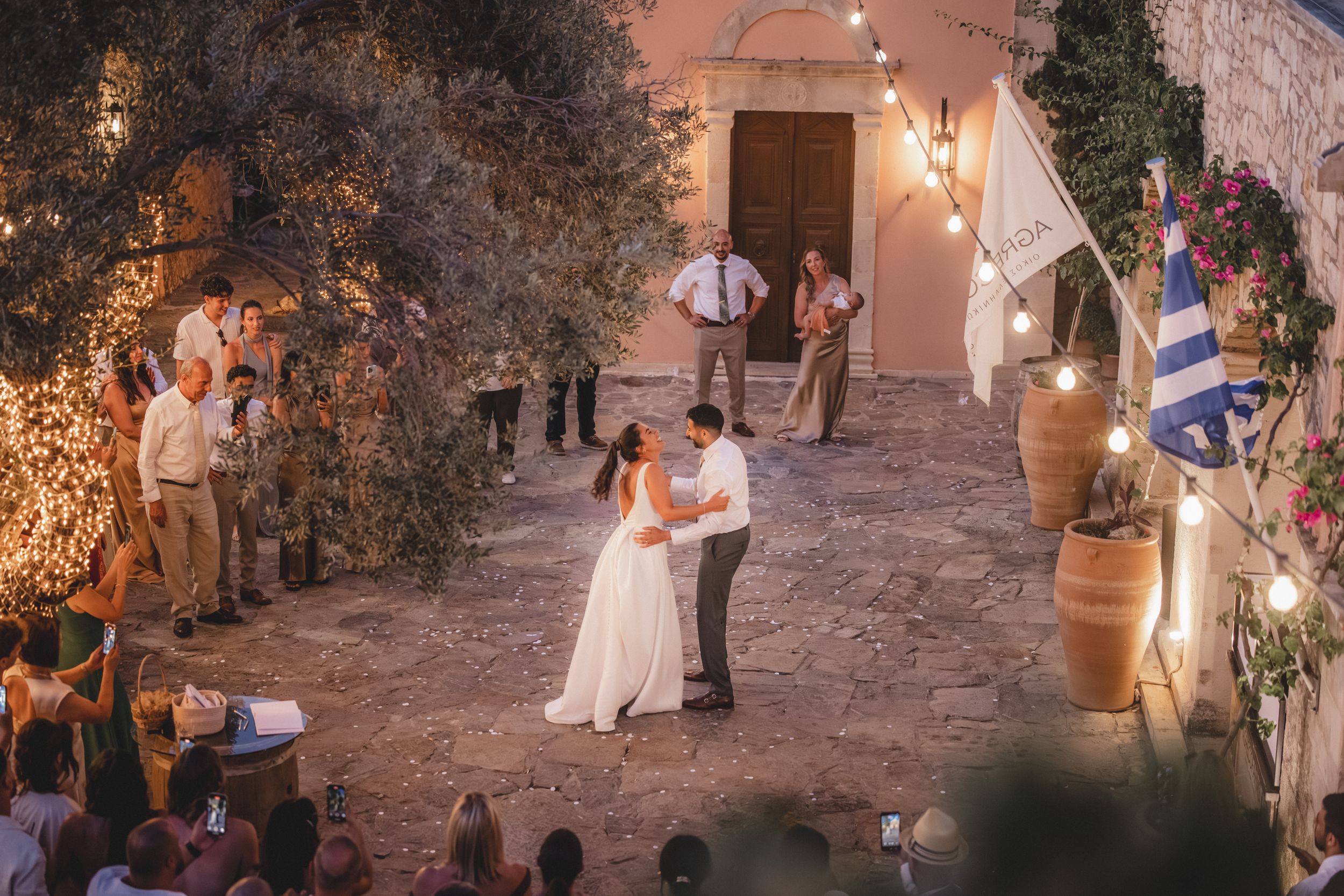 Stone courtyard decorated with string lights hosts an evening wedding celebration.