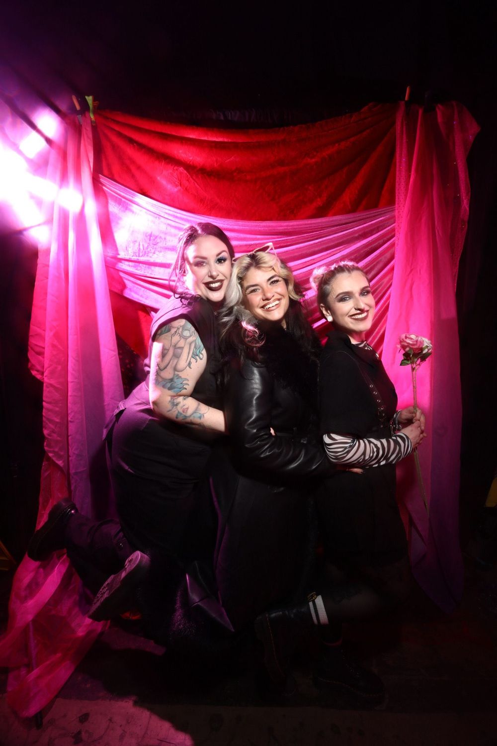 Group photo against pink fabric backdrop with dramatic lighting.