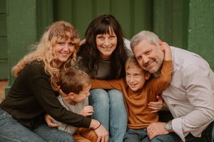 A family shares joyful laughter and embraces while taking photos outdoors on an autumn day.
