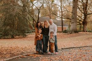 A group poses for a portrait on a leaf-covered path during fall season.