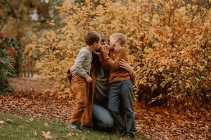 Joyful outdoor autumn photo session with warm brown tones and fallen leaves.