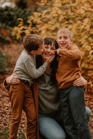 Joyful family moment captured in autumn setting with warm orange and brown tones among fallen leaves.