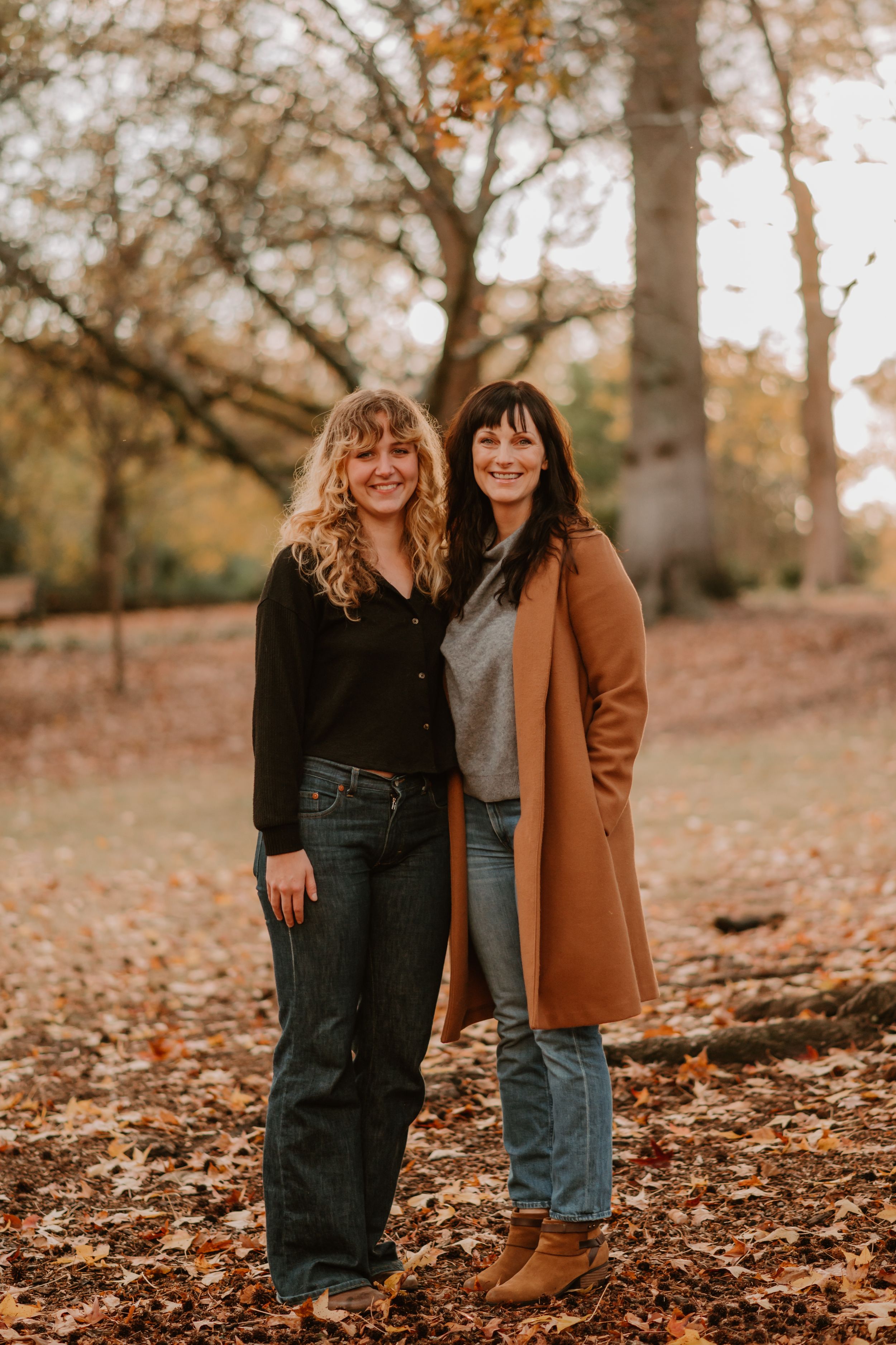 Casual outdoor family photoshoot with warm autumn tones and fallen leaves in the background.