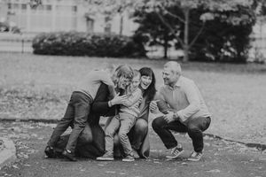 A monochrome photo shows a small family sharing a gentle moment together on a grassy lawn.