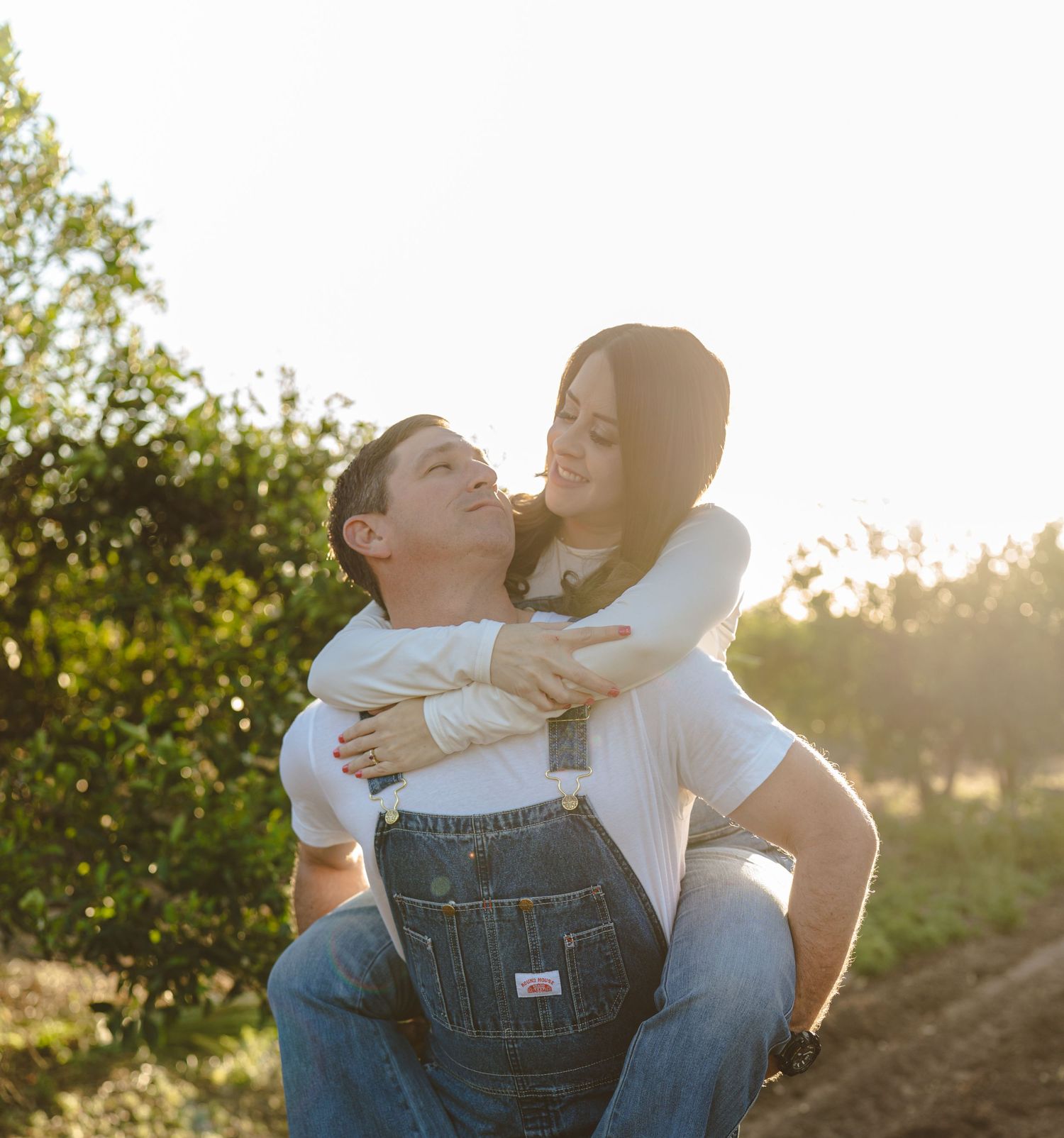 A couple shares a tender moment in an orchard during golden hour.