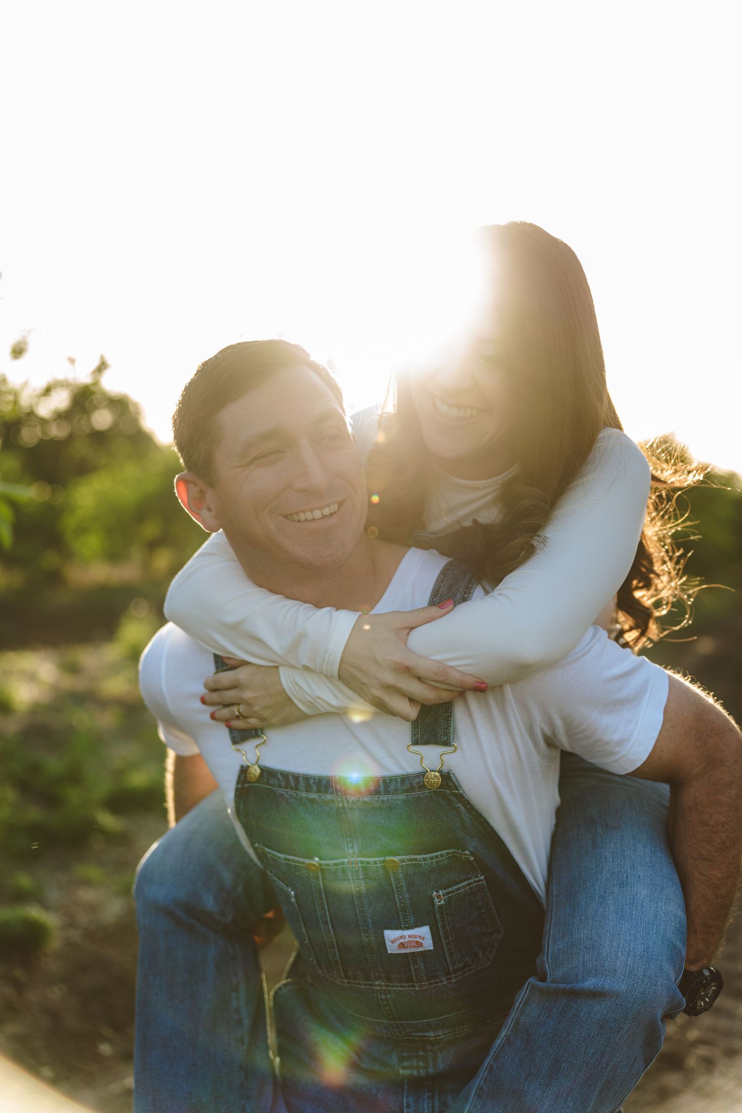Couple in casual attire sharing intimate moments during golden hour sunset photoshoot.