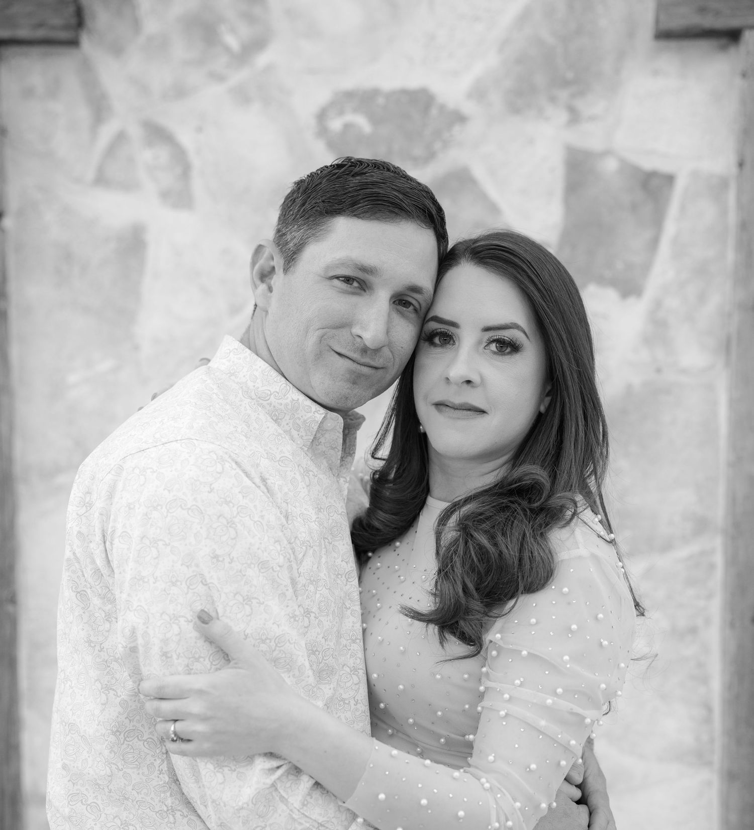 Black and white portrait series showing couple in white attire against textured wall.