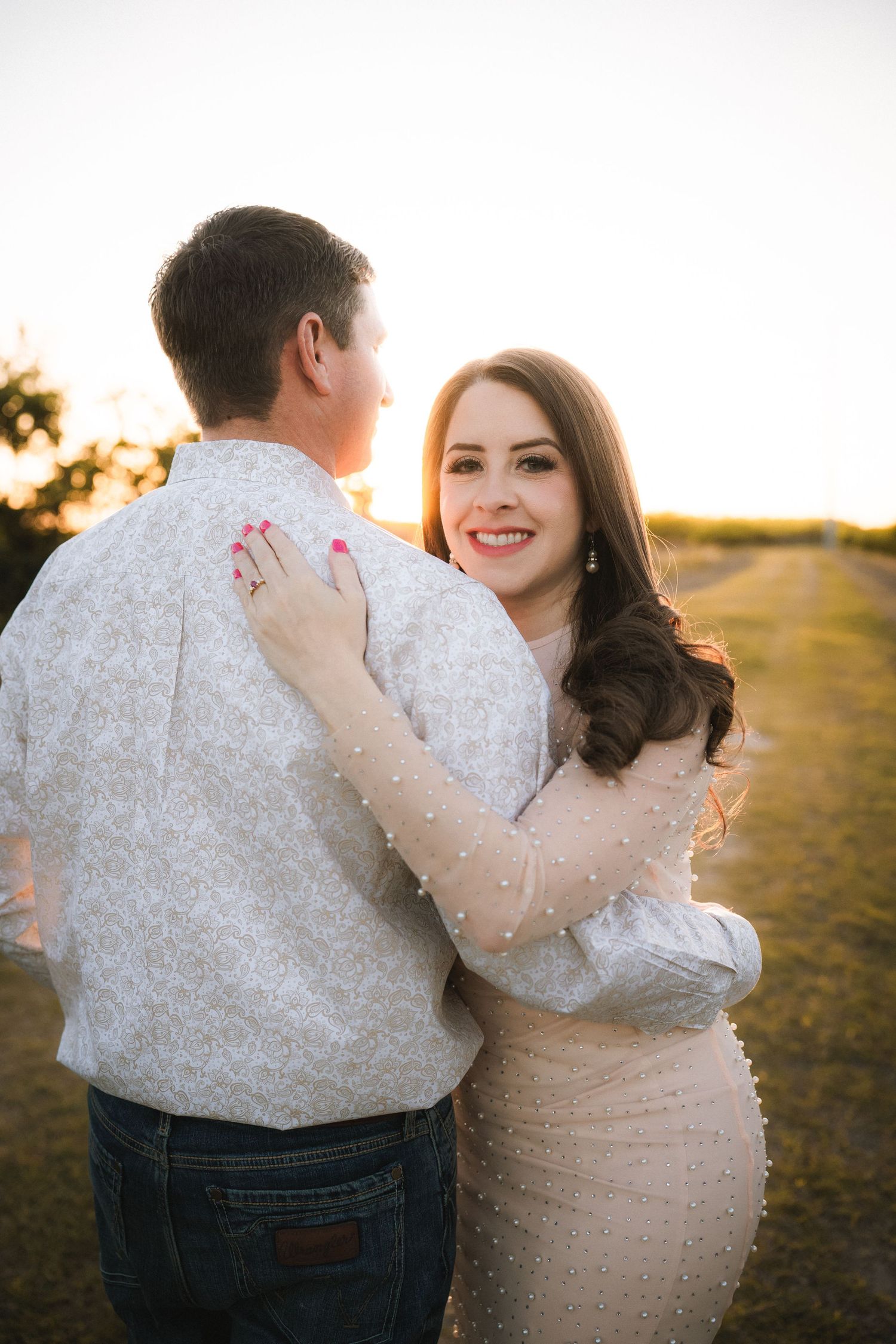 Couple in white clothing sharing intimate moments during sunset photoshoot.