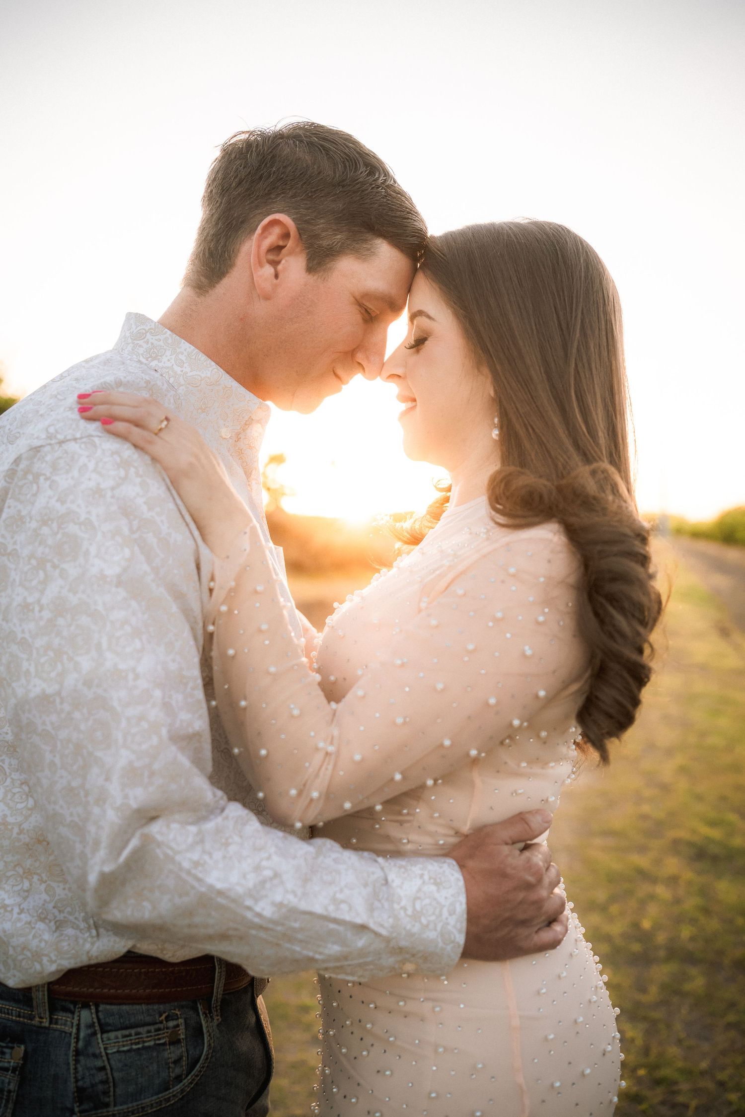 Tender embrace between couple in white attire during golden hour photography session.