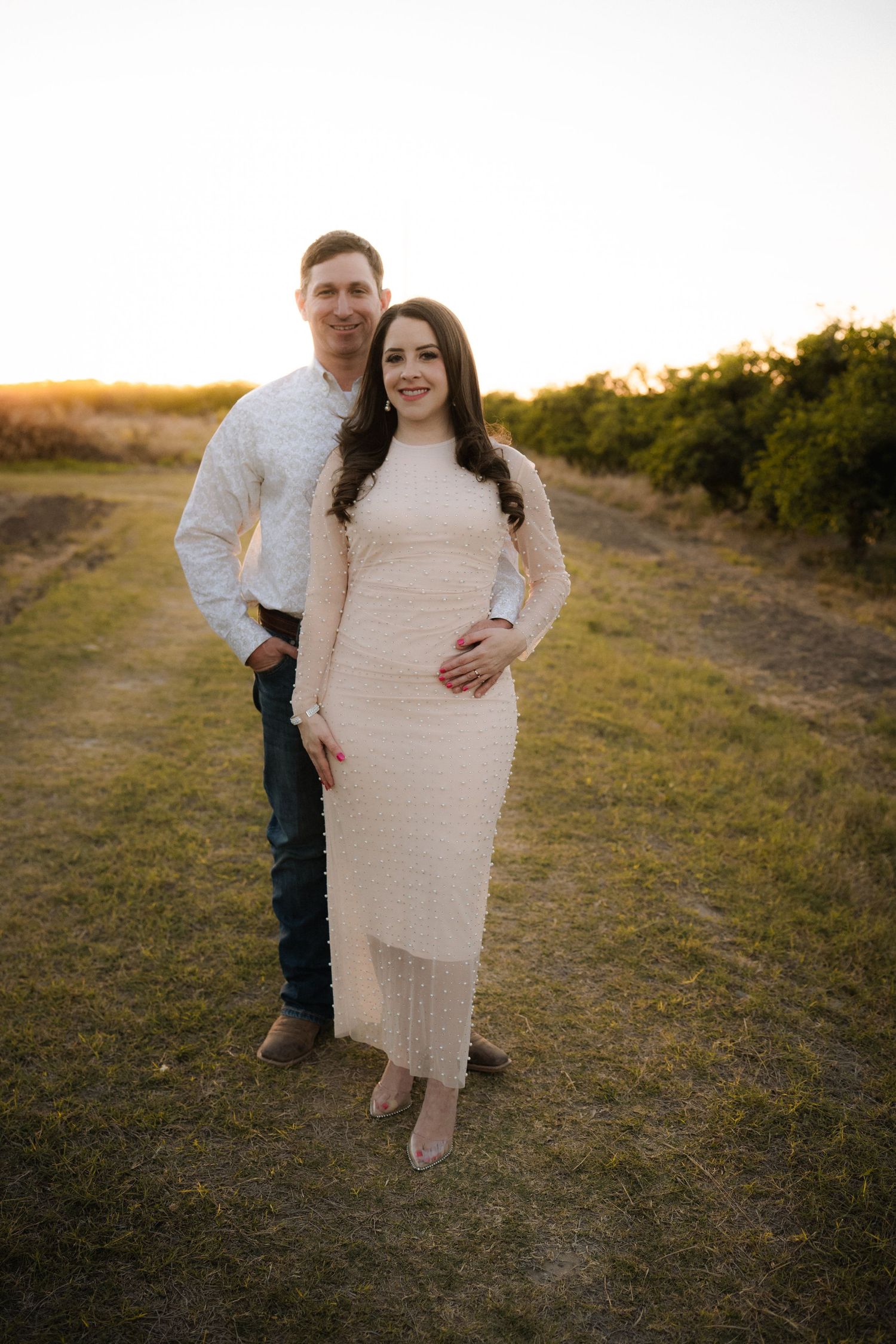 Couple walking together on grassy path during sunset engagement photo session.