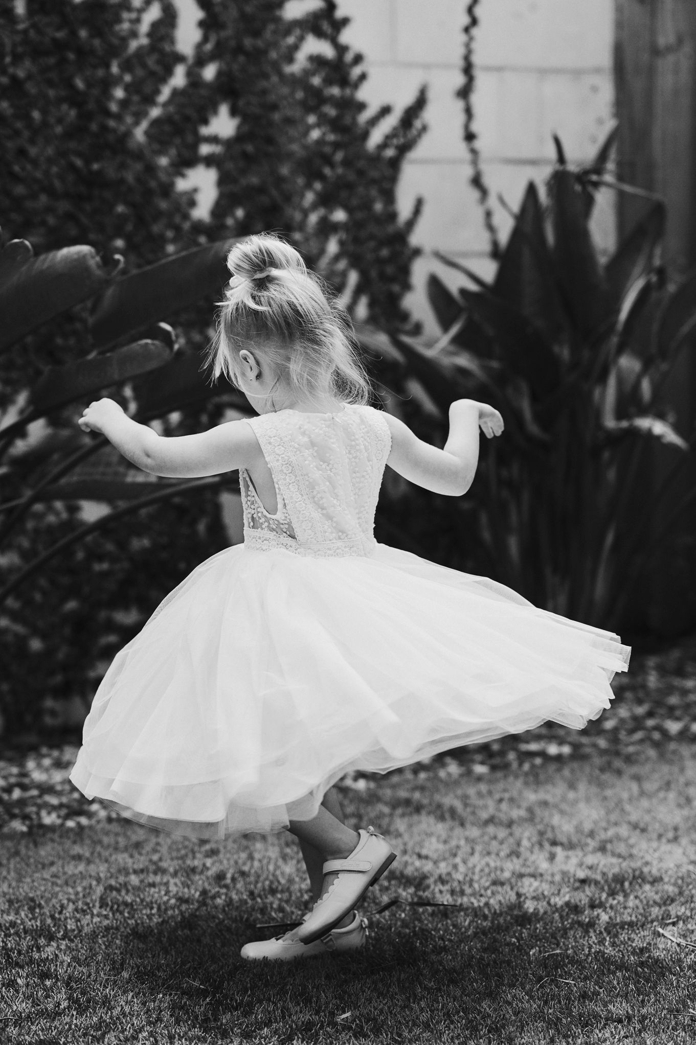 Sequence of a twirling white dress captured in black and white on a grassy lawn.