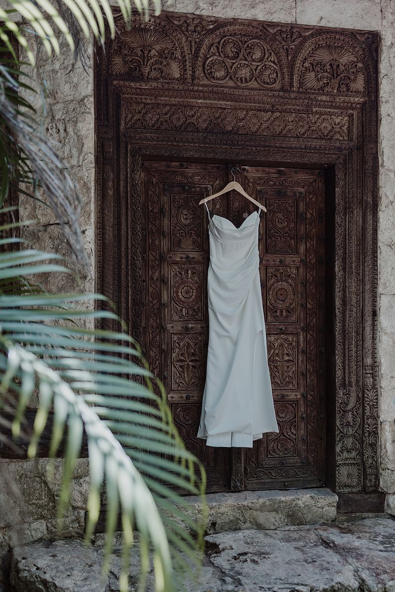 Wedding dress hanging on ornate wooden door at Kuha Casa del Agua, elegant wedding details in Mexico.