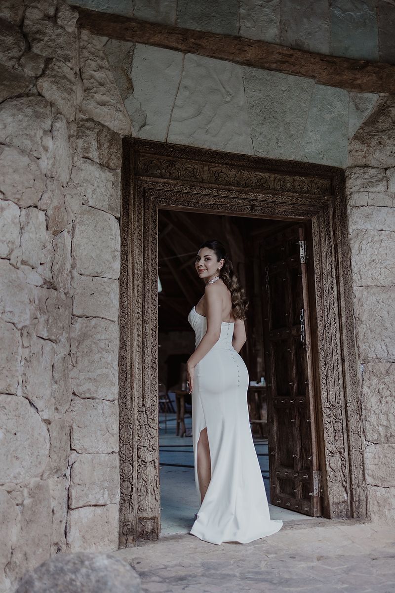 Bride in white gown standing in stone doorway at Kuha Casa del Agua, wedding photographer in Mexico.