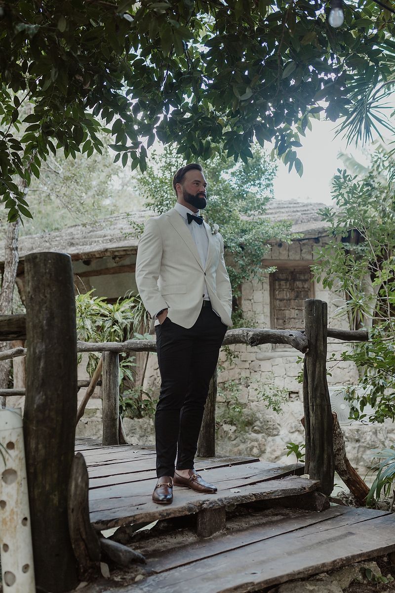 Groom walking wooden bridge surrounded by tropical greenery at Kuha Casa del Agua, destination wedding Riviera Maya.