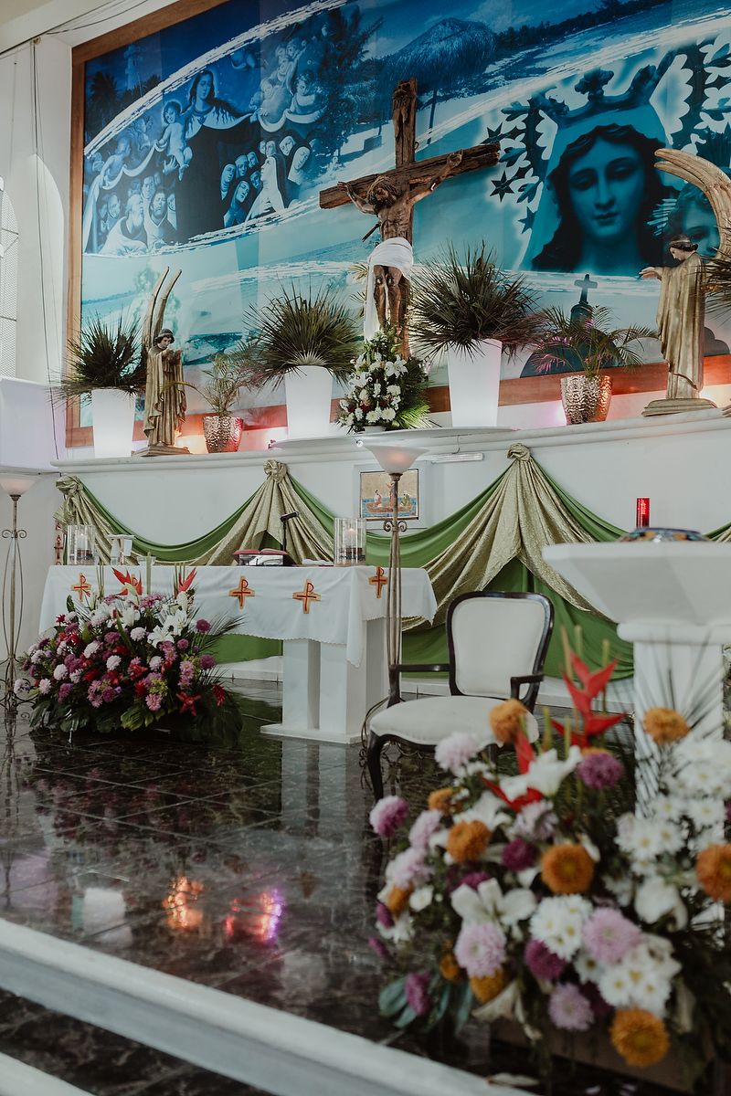 Religious altar decorated with flowers, draped fabric, and a mural featuring spiritual imagery.
