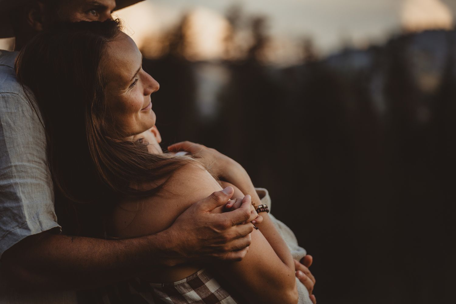 Intimate black and white portrait of a couple embracing tenderly in soft natural lighting.