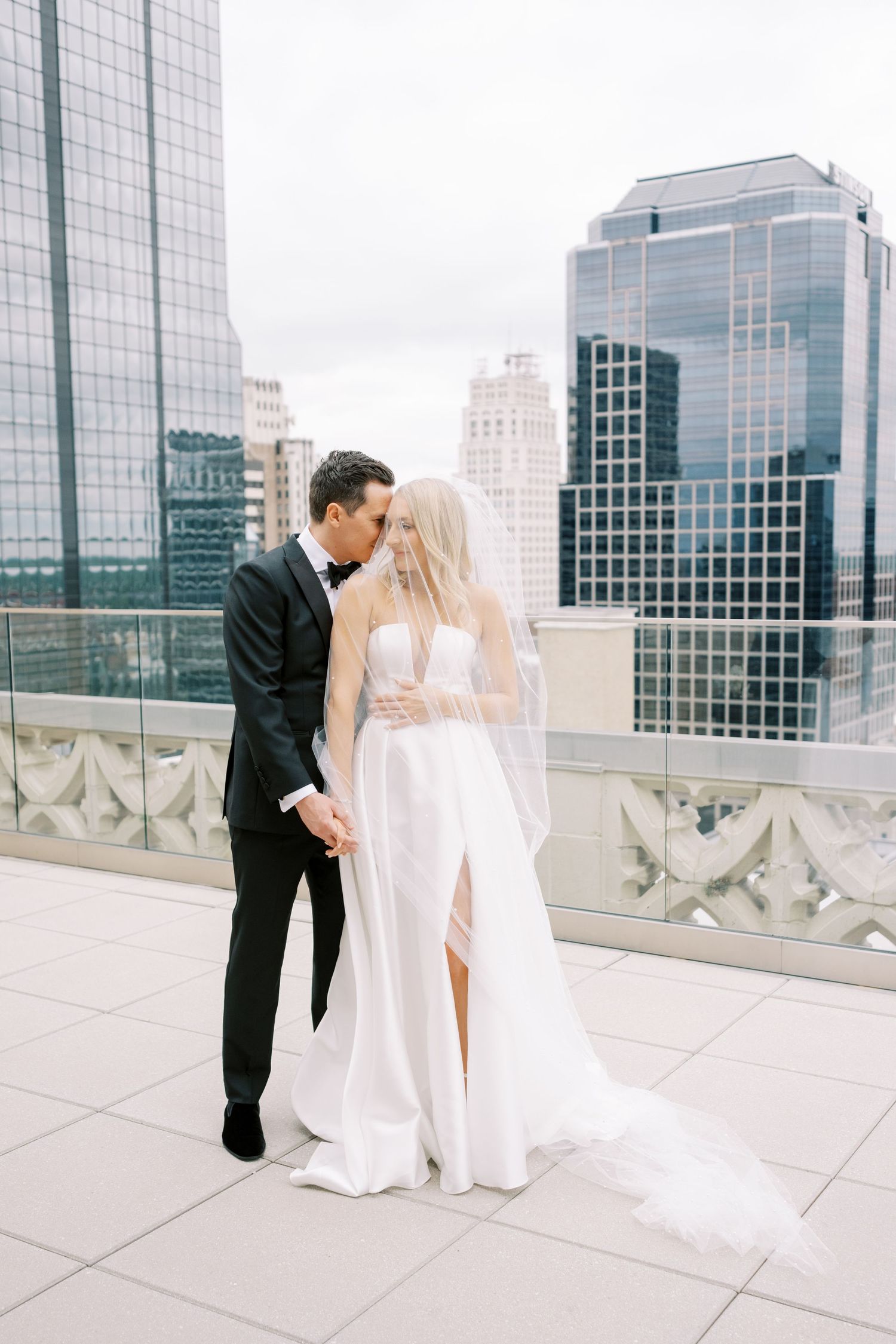 Romantic rooftop wedding moment with city skyline backdrop.
