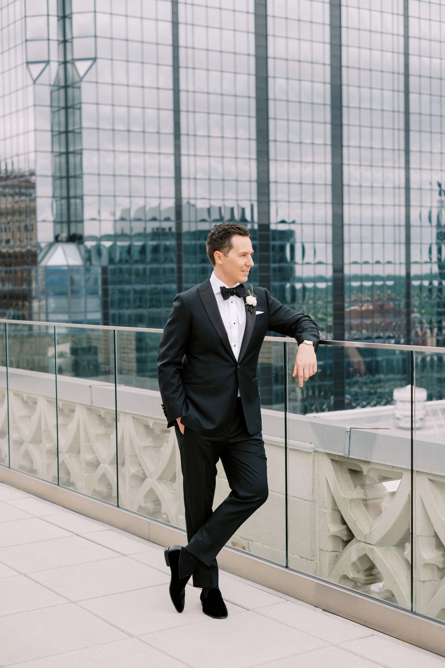Elegant formal wear against modern glass building backdrop on rooftop terrace.