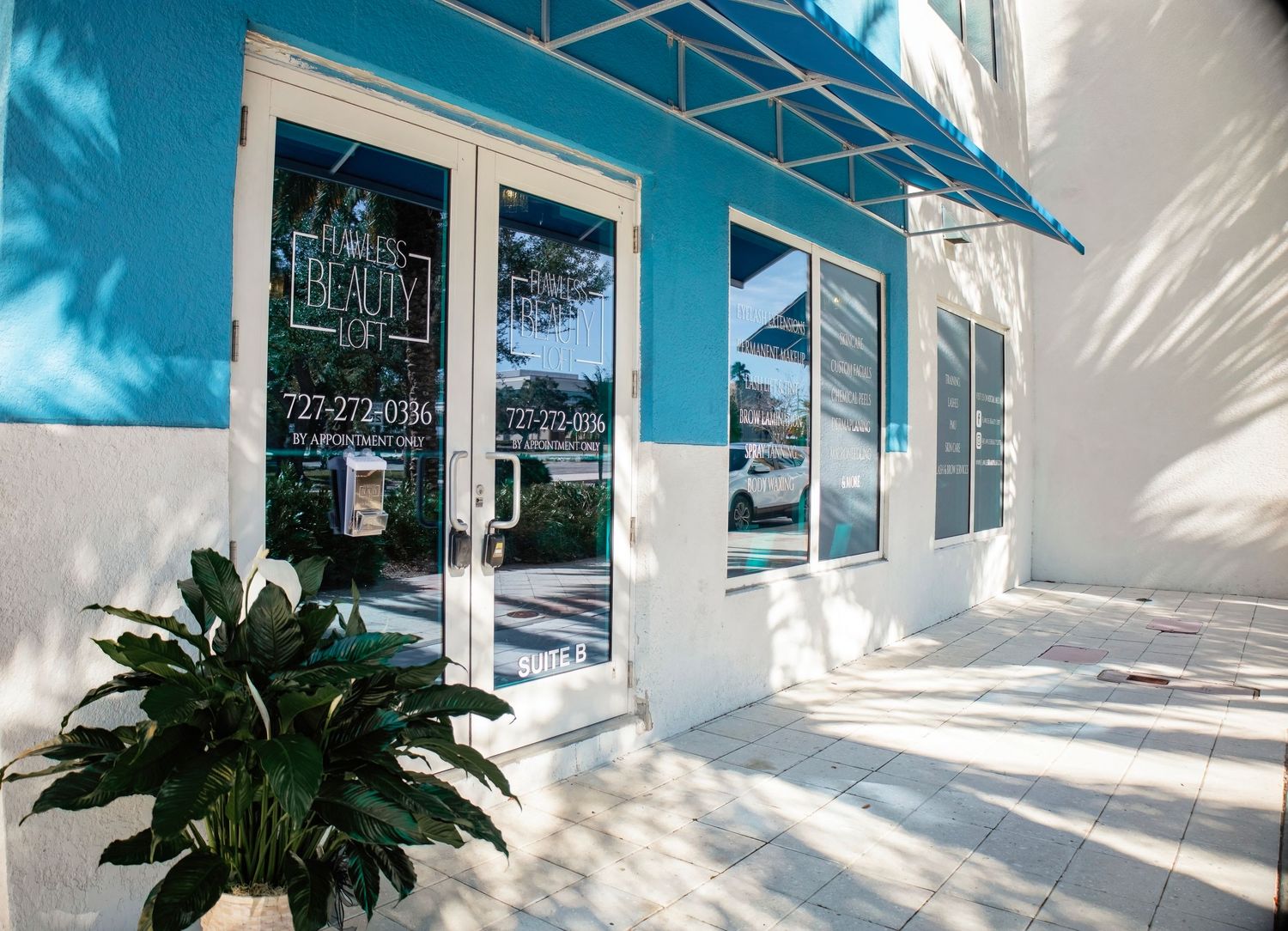 Modern white storefront exterior with palm trees and blue walls creates an upscale retail atmosphere.