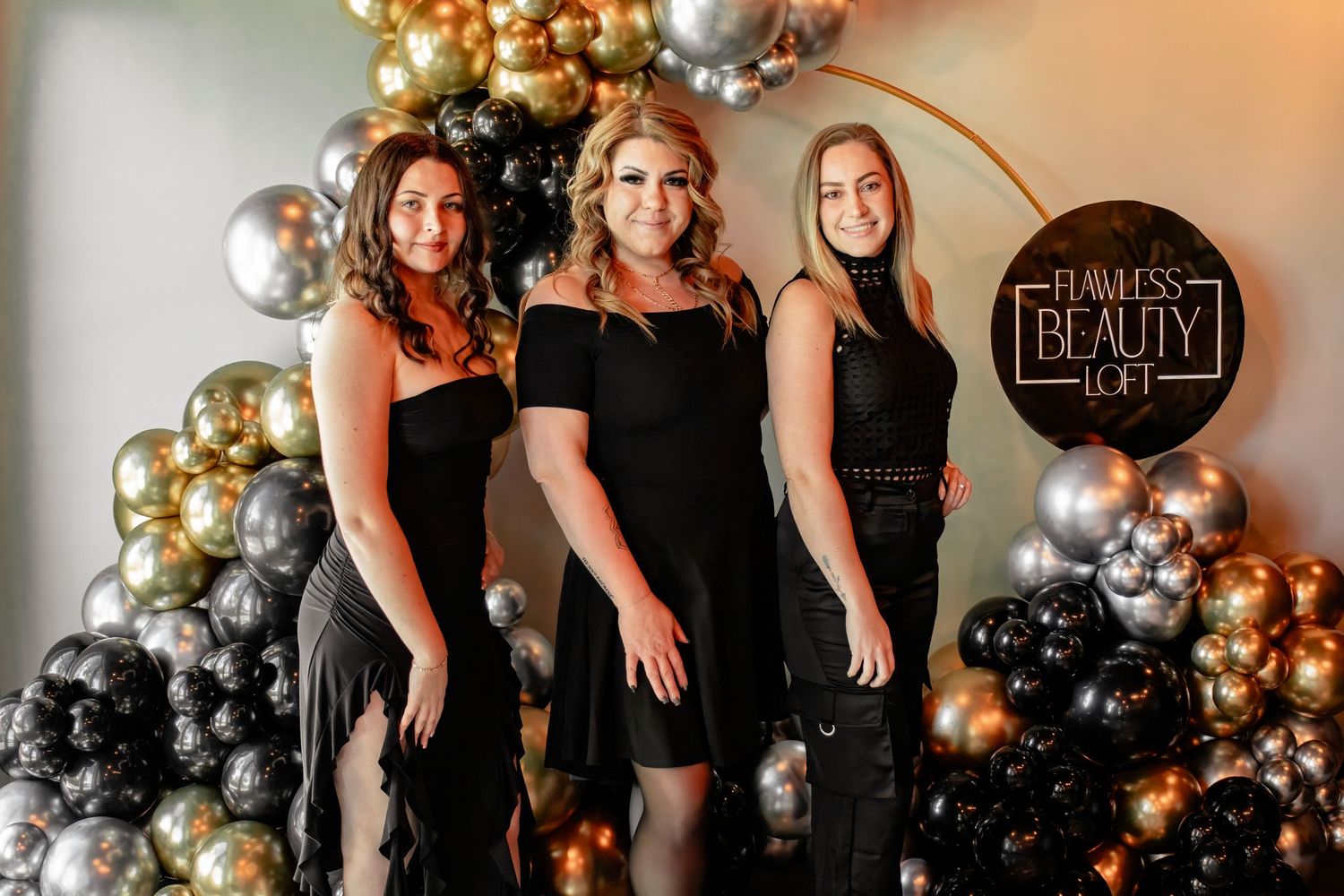Black and gold balloon arch creates elegant backdrop for special event photography.