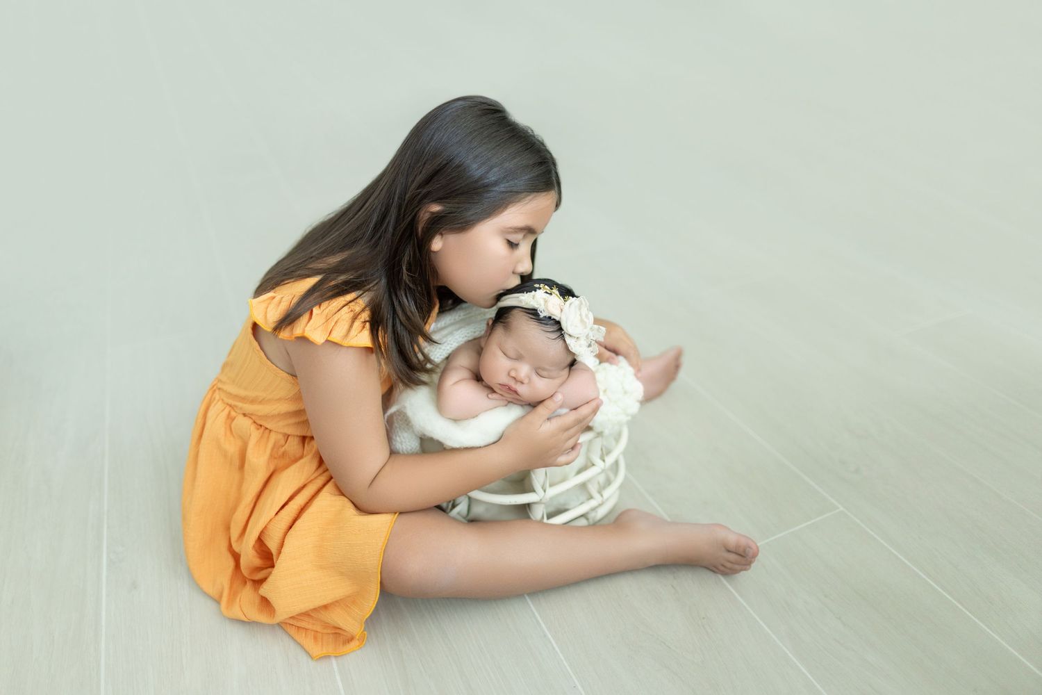 Tender moment during newborn portrait session on light green background.