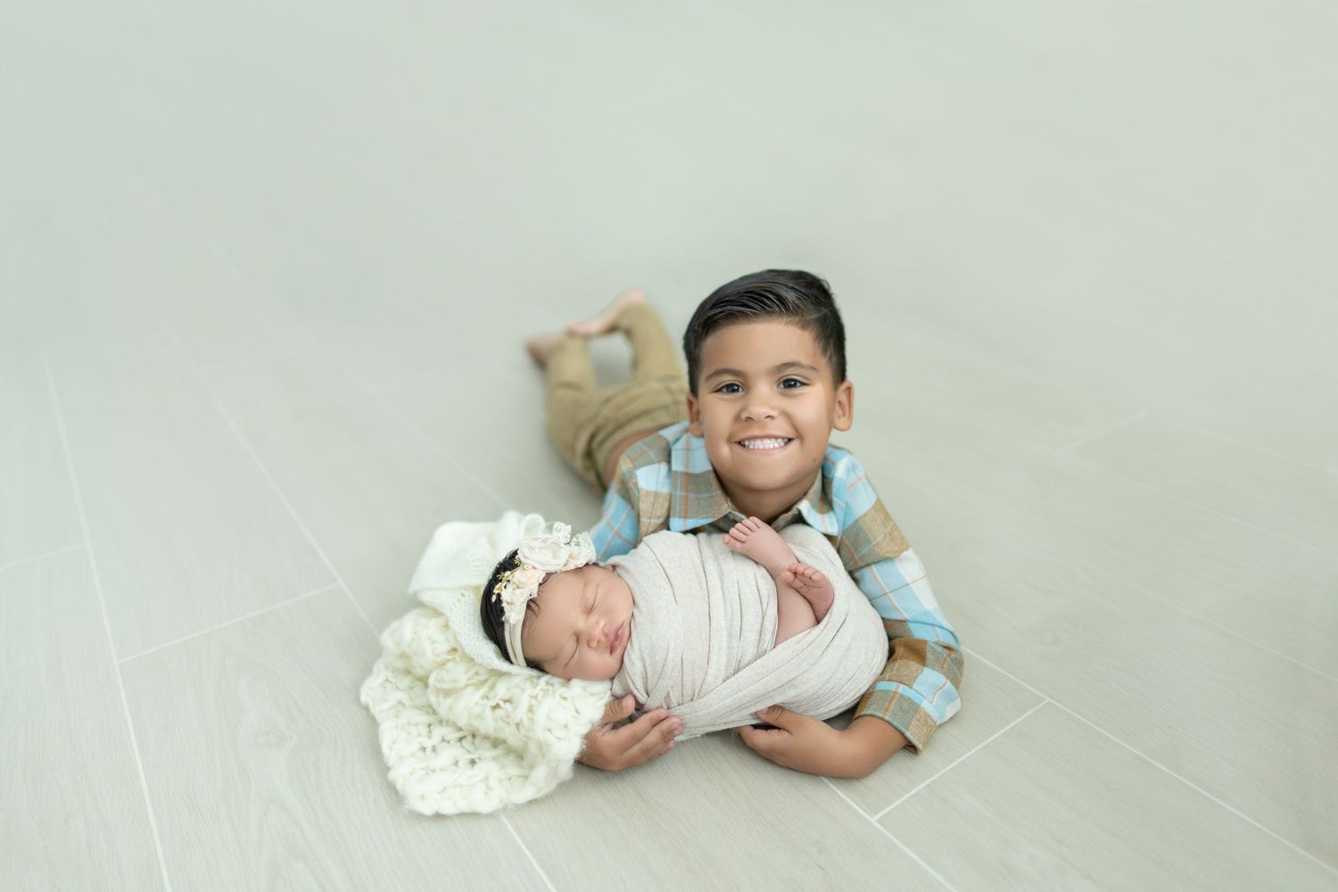 Sleeping newborn baby dressed in white on cozy blanket during professional photo session.