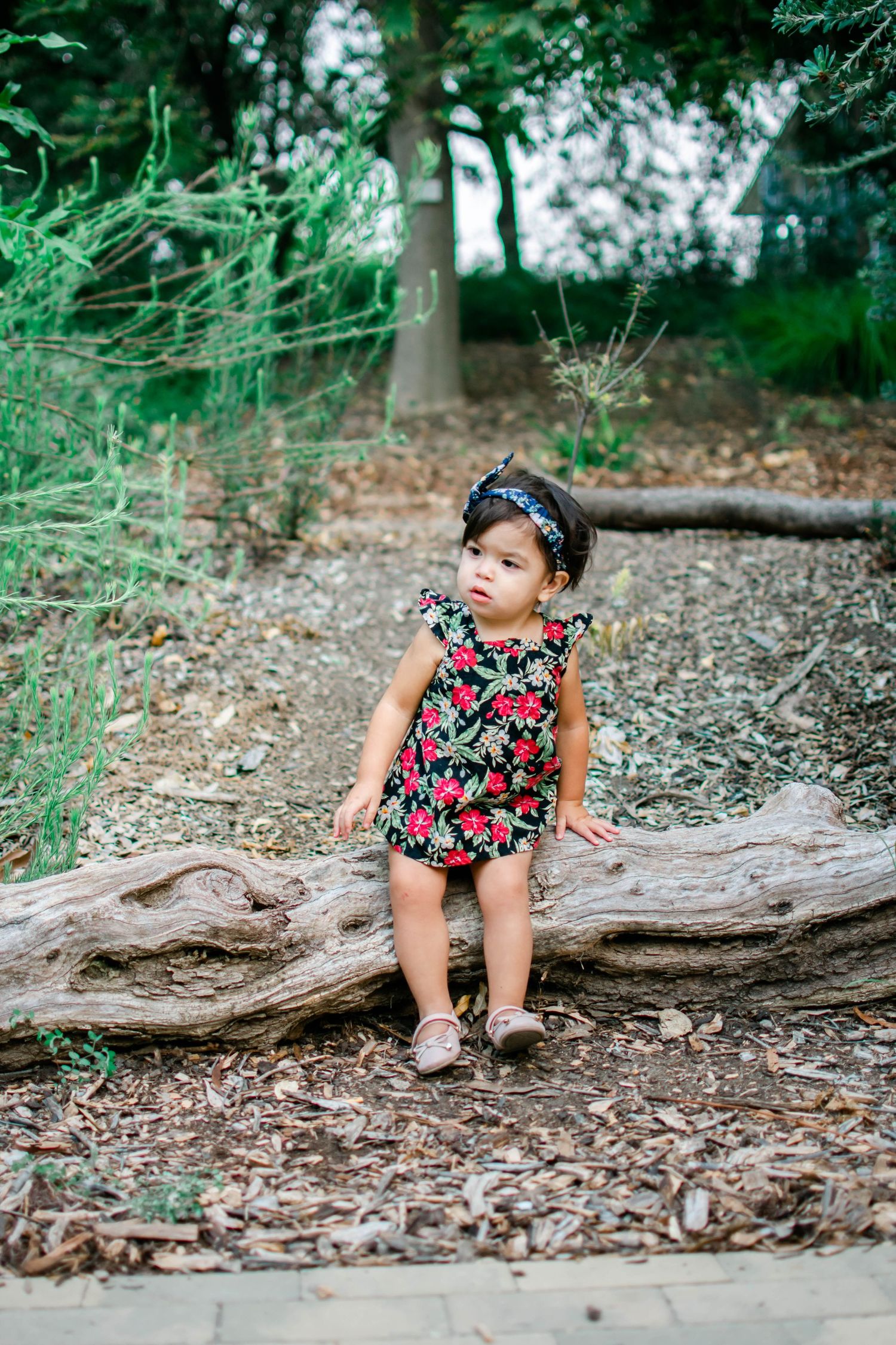 Candid outdoor photography sequence on a fallen log with floral outfit and natural surroundings.