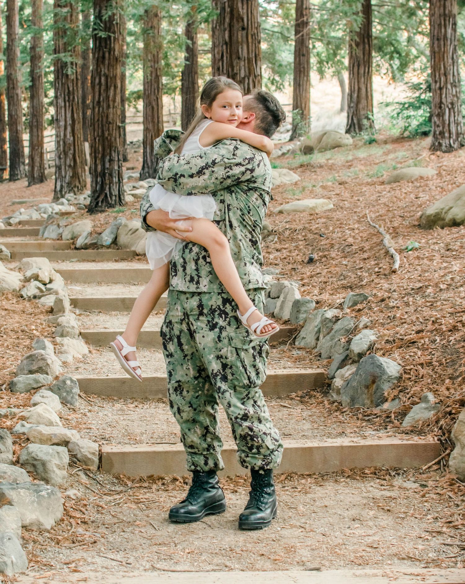 A playful moment captured between service member and child on outdoor stone steps.