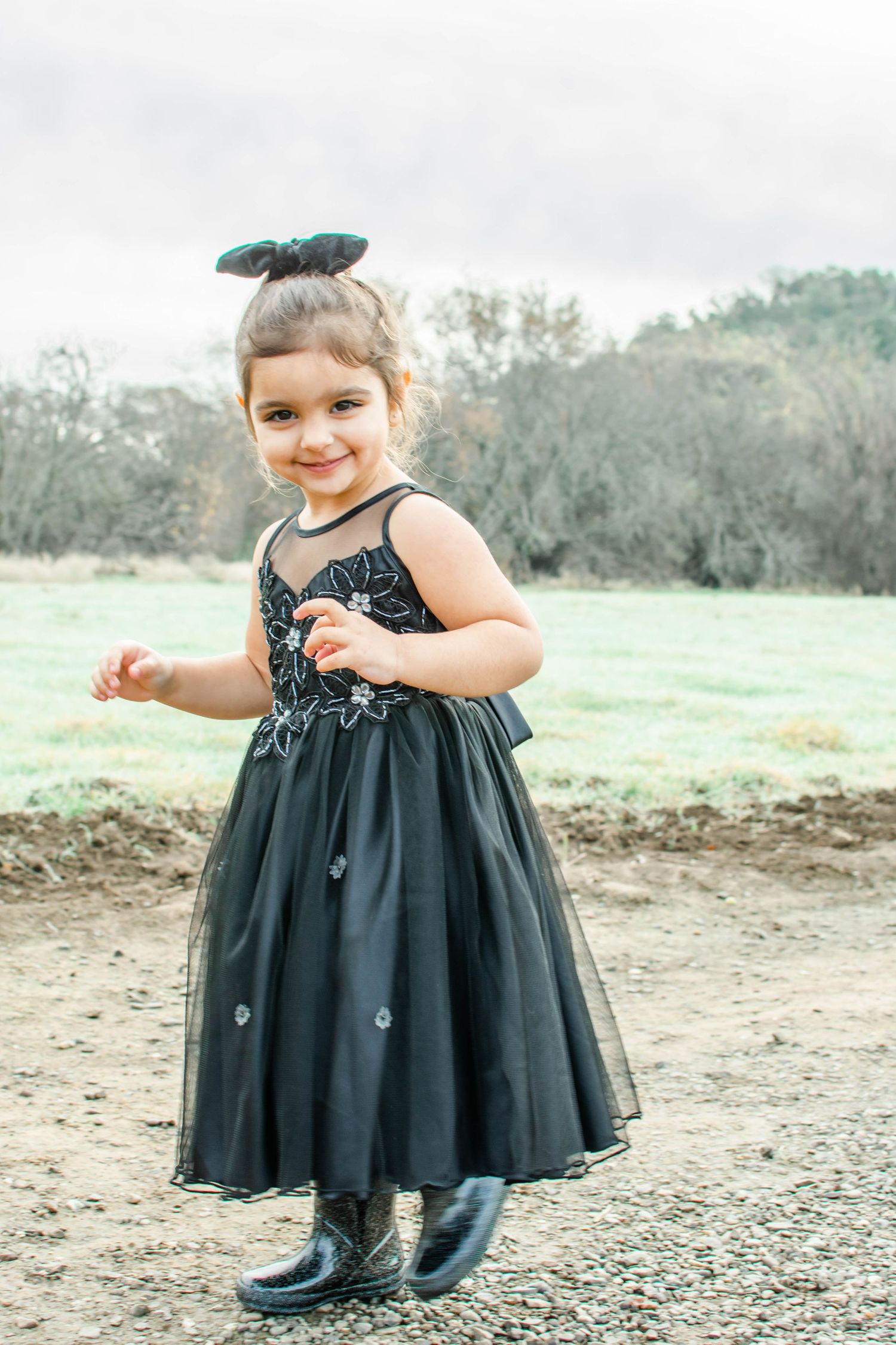 Series of playful poses in a black tulle dress against an outdoor natural setting.