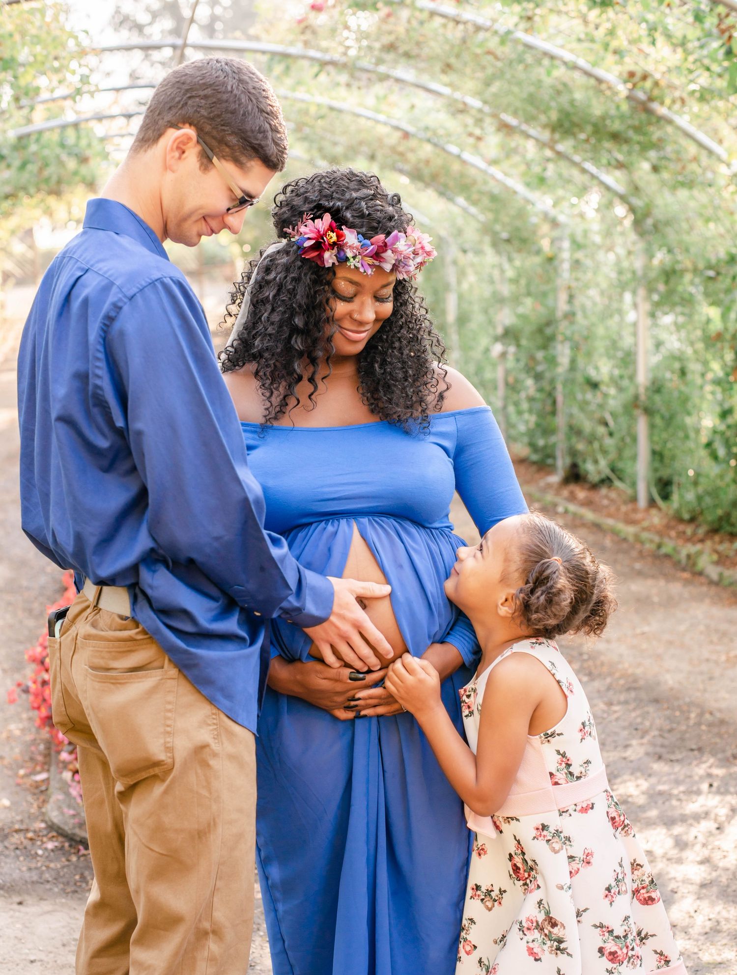 Family in coordinated blue and beige outfits posing together in a garden setting.