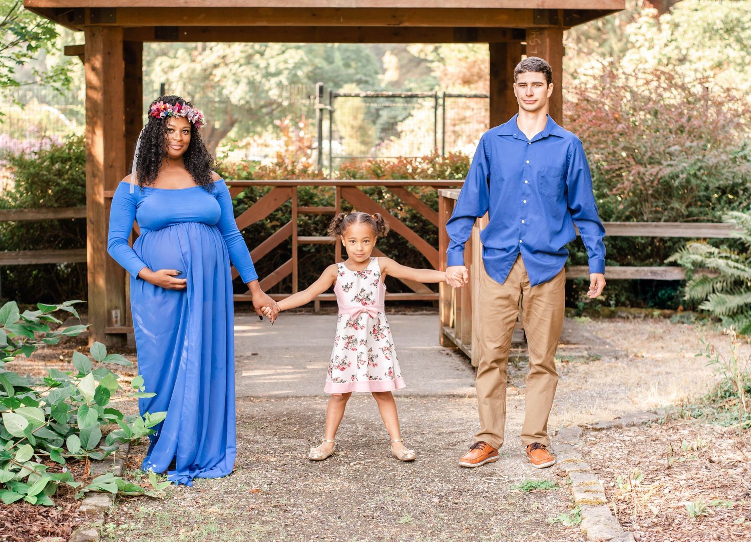 Family photoshoot in a garden setting with people wearing coordinated blue and floral outfits.