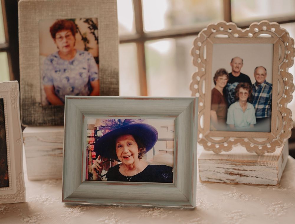 Collection of vintage family photographs displayed in decorative frames on a white surface.
