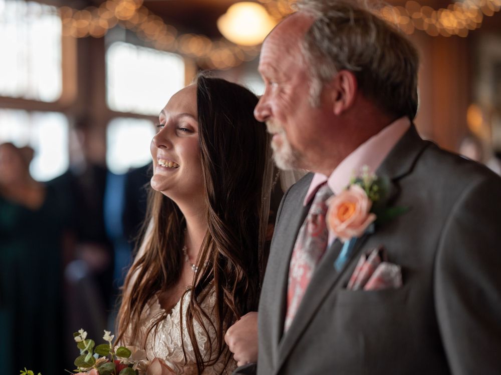 Wedding attendees share a candid moment with peach floral boutonnieres in indoor reception venue.