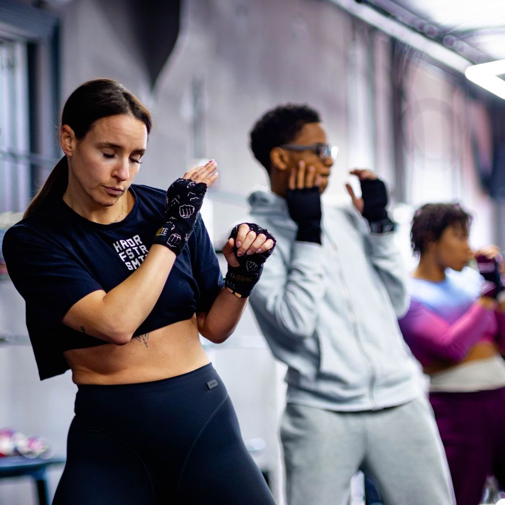 Athletes training together in a gym wearing workout attire and gloves during a fitness session.