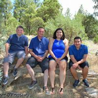 Family of four sitting on log outdoors wearing coordinating blue outfits.
