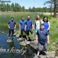 Family of seven standing on rocks by pond with lake a family text overlay.