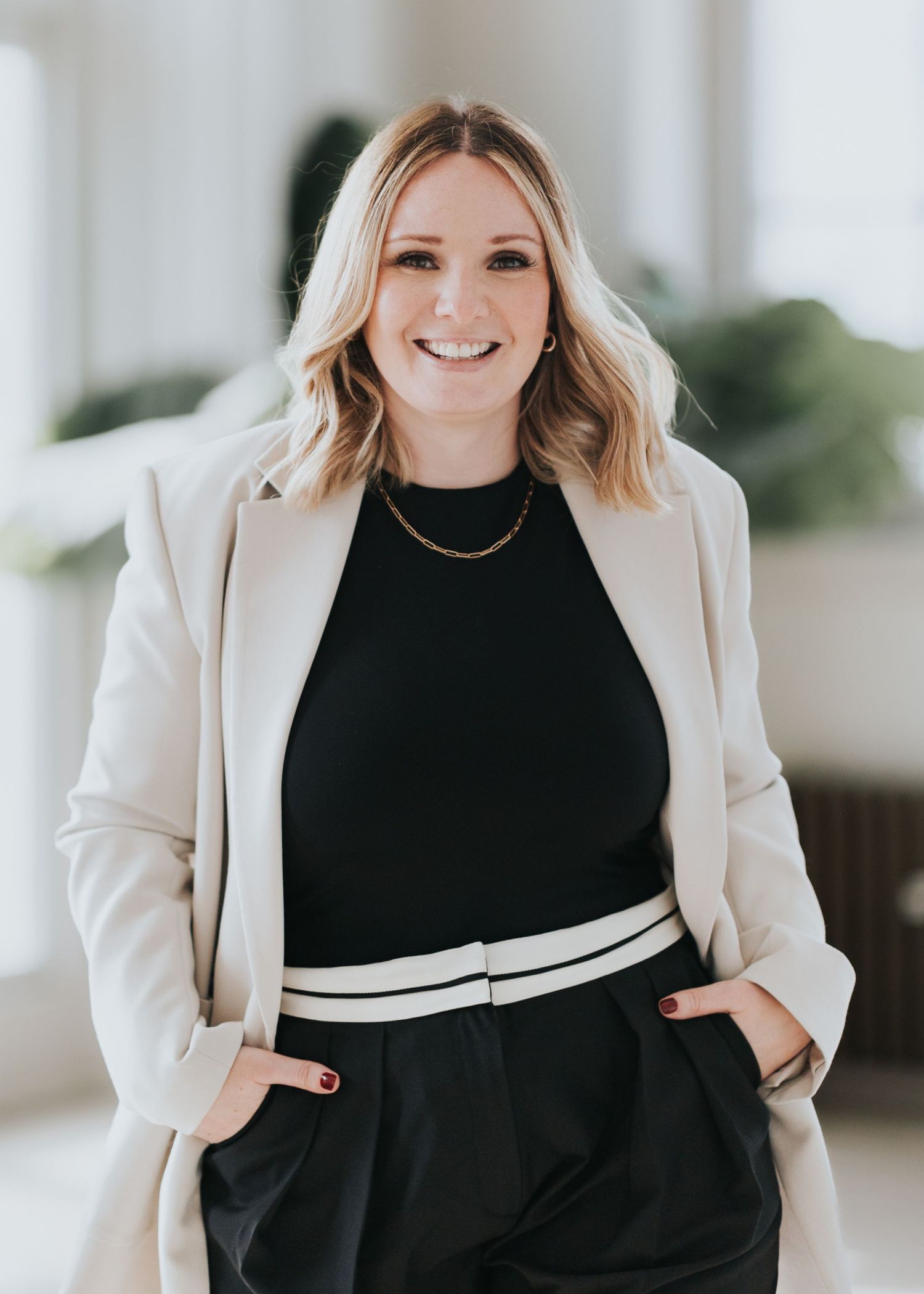 Professional wearing a black sweater with white stripe detail and cream blazer shown in multiple poses against light background.