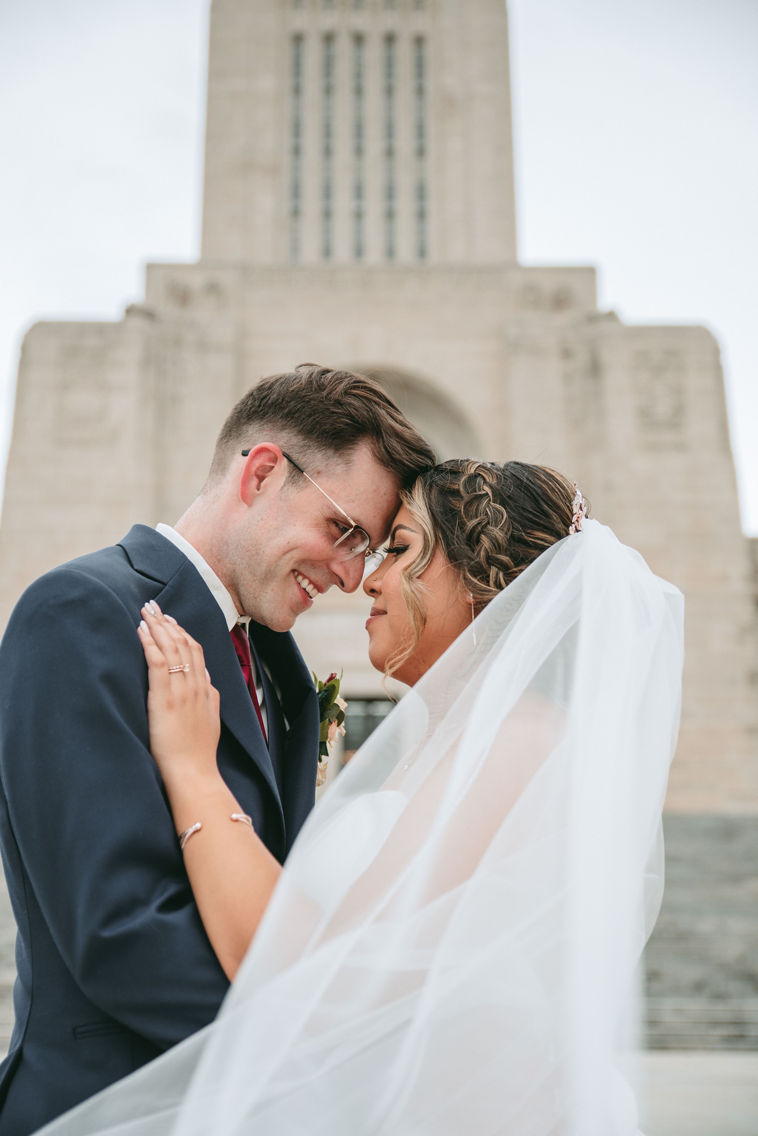 A romantic wedding moment captured in front of a grand stone building.