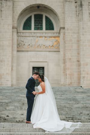 A tender wedding moment captured on the grand steps of a historic building.