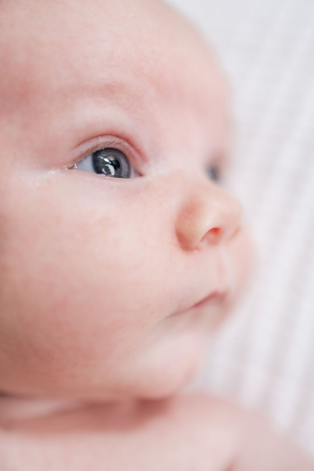 Close up macro shot of a baby's bright eye and soft skin in a dreamy high key style photograph.