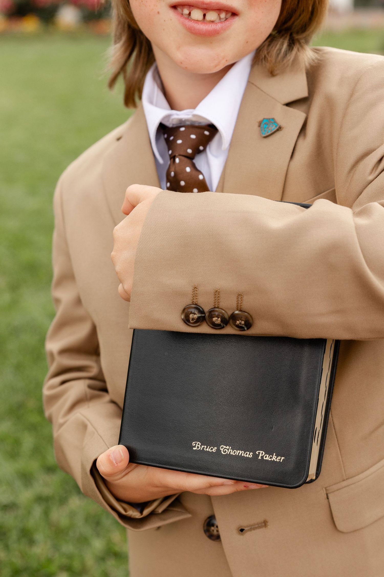 boy in brown suit holding scriptures with his name on them
