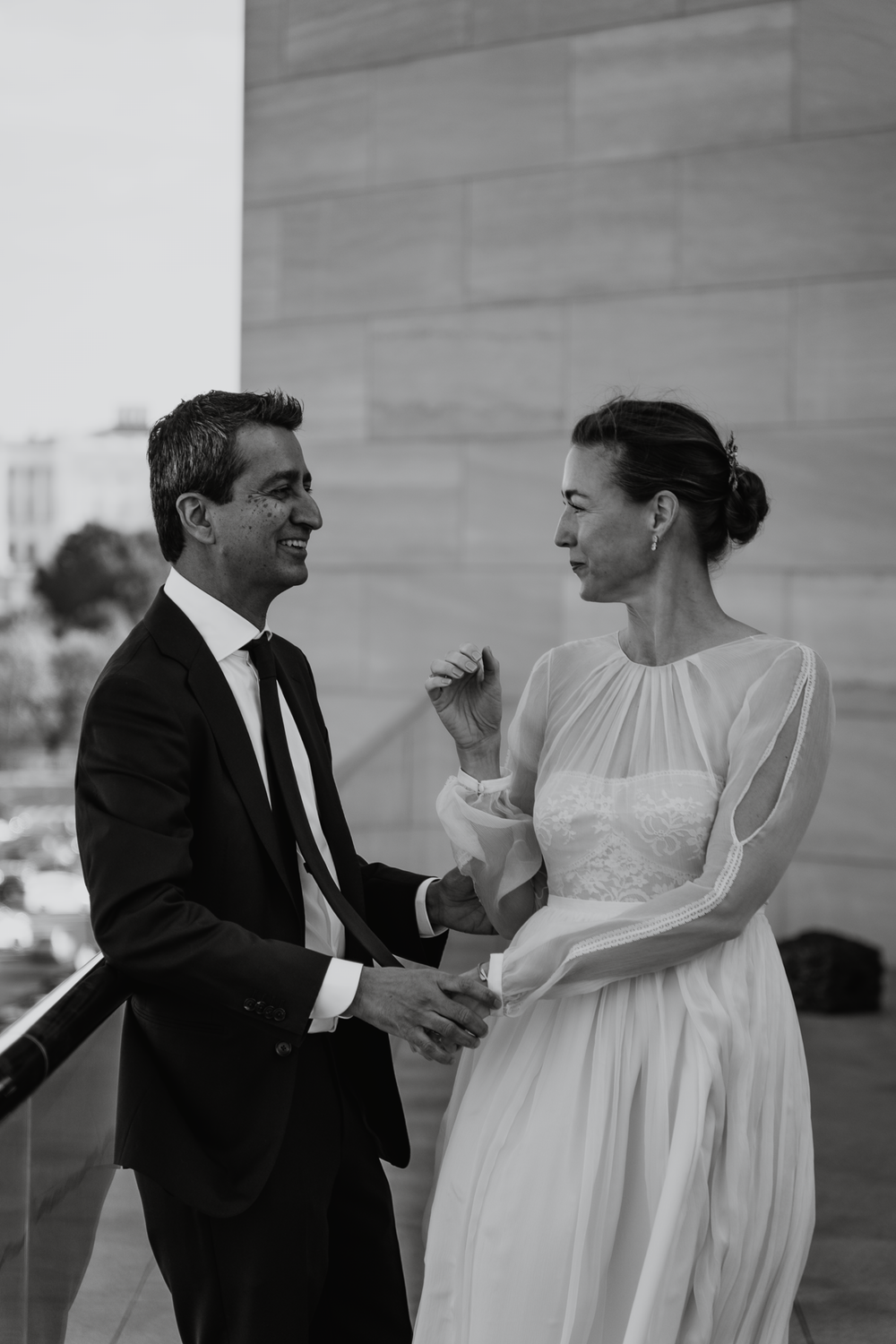 Black and white photo of a couple in formal wedding attire sharing an intimate moment and conversation.
