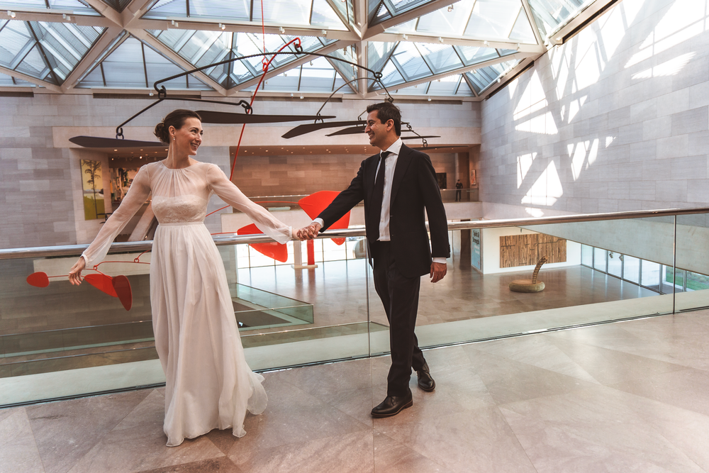 Two people in formal attire dancing together in a modern glass-enclosed space with natural light.